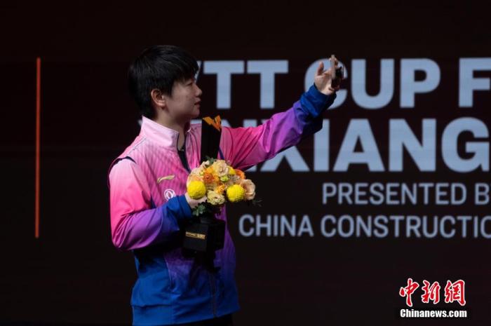 资料图：图为孙颖莎手捧奖杯和鲜花自拍。 阚力 摄